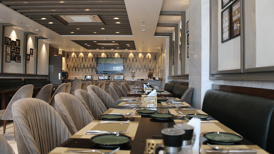 A well-arranged dining space featuring tables with chairs and neatly set cutlery at  BluSalzz Residence, Amritsar